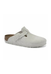 Zoccolo in suede grigio chiaro con schiena rialzata, cinturino regolabile e suola in gomma leggera. Presenta una finitura liscia e una soletta in sughero naturale.