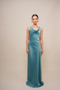 Robe de soirée en satin teal avec un décolleté cowl, sans manches et silhouette fluide, reposant au sol avec une texture lisse.