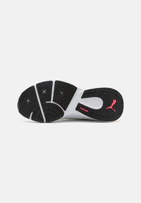 Suela de goma negra con un patrón de ondulación, que presenta una entresuela blanca y acentos en rosa del logo de Puma.