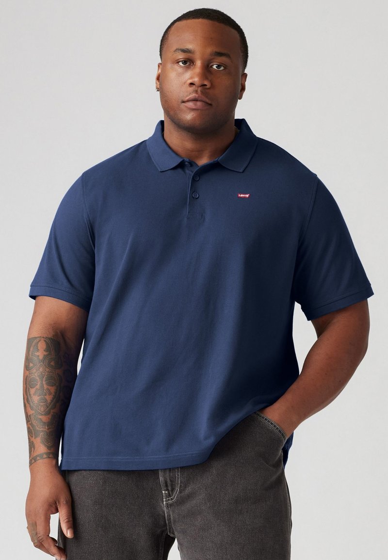 Marineblauwe polo met een klassieke kraag, korte mouwen en een klein rood Levi's-logo op de borst. Zacht katoen, comfortabele pasvorm.