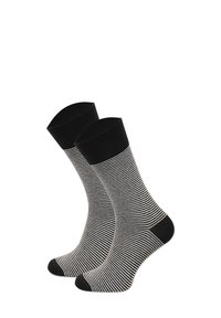 Czarno-białe paskowane skarpetki z prążkowanym ściągaczem, gładką teksturą oraz kontrastującymi czarnymi wzmocnieniami na palcach i pięcie.