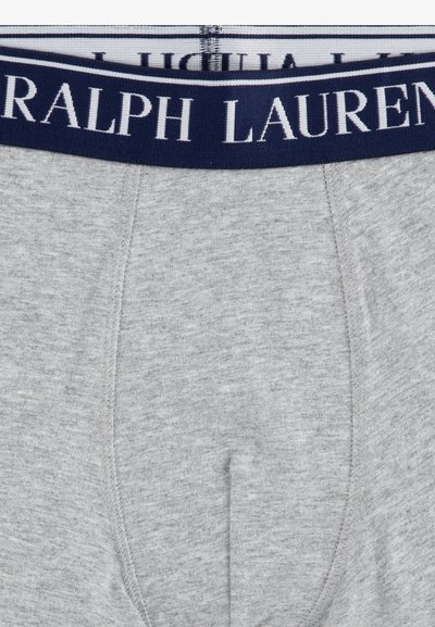 Boxer ajustados de algodón gris con cinturilla elástica azul marino que presenta "RALPH LAUREN" impreso en blanco. La tela tiene un aspecto suave y texturizado.