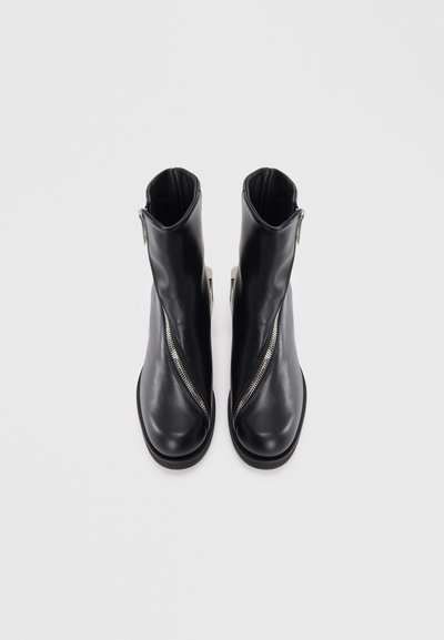 Crne kožne čizme do gležnja sa bočnim zatvaračem, zaobljenim prstima i glatkom teksturom. Imaju minimalistički dizajn s niskom petom.