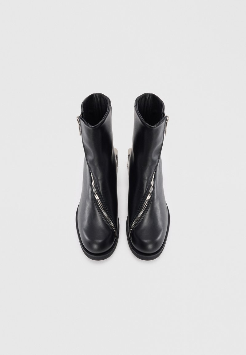 Stivaletti neri in pelle con cerniera laterale, punta arrotondata e superficie liscia. Presentano un design minimalista con tacco basso.
