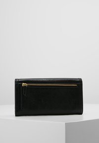 Portafoglio in pelle nera con finitura testurizzata, dotato di una zip dorata sulla parte anteriore e un design rettangolare elegante.