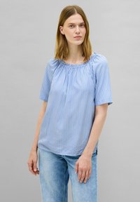 Blusa blu a righe con maniche corte e scollo arricciato, abbinata a jeans in denim azzurri. Tessuto morbido con vestibilità rilassata.