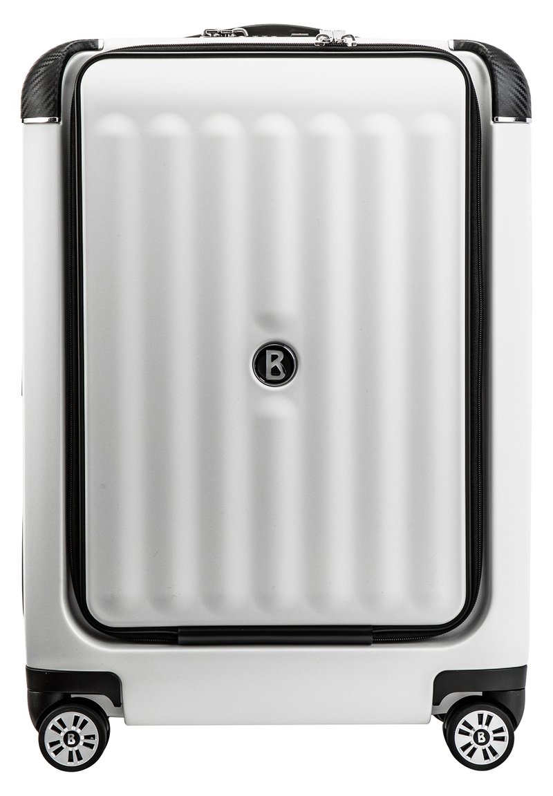 Trda kovček v srebrni barvi z navpičnimi rebri, okrašen z črnim zadrgo in kolesi z okroglo zasnovo in logotipom.