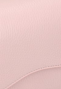 Material din piele roz cu o suprafață texturată. Prezintă o curbă netedă de-a lungul marginii, conturată cu detalii cusute.