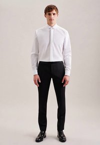 Weißes Hemd mit Kragen, kombiniert mit schwarzer Hose. Das Hemd ist schmal geschnitten und hat eine glatte Textur; die Hose ist maßgeschneidert.