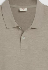 Beige polo t-shirt med ribbad krage, två-knapp placket och en liten logotyp. Tillverkad av mjukt, texturerat tyg med en slim fit design.