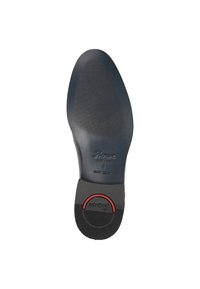 Semelle de chaussure en caoutchouc noir avec une texture antidérapante, comportant un accent circulaire rouge proéminent et le logo de la marque. Taille 8 visible près du talon.