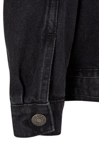 Fekete farmerkabát mandzsettája látható varrással és egy kerek fémgombbal, amin az "Urban Classics" felirat szerepel.