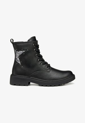 Bottine noire en cuir à lacets avec semelle épaisse et décoration étoile argentée scintillante sur le côté.