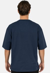Donkerblauw katoenen T-shirt met korte mouwen, een ronde hals en een losse pasvorm. Gladde textuur, effen ontwerp, zonder zichtbare logo's of patronen.
