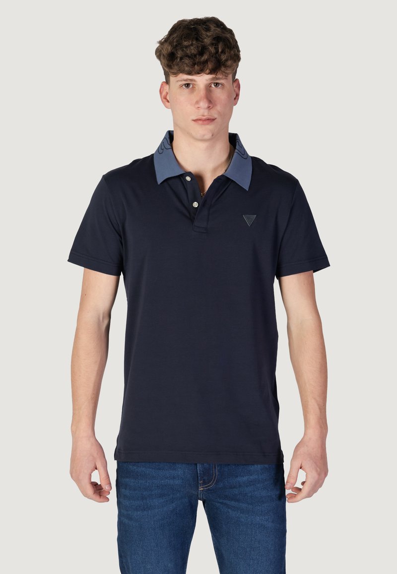 Polo navy in cotone con colletto azzurro chiaro, caratterizzato da un logo triangolare sul petto e maniche corte. Design a taglio dritto.