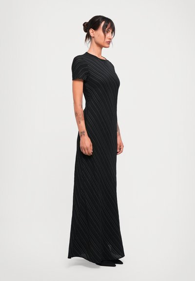 Black maxi dress with short sleeves, featuring vertical white stripes. Made of a smooth fabric, the design is fitted at the top, flaring at the bottom.