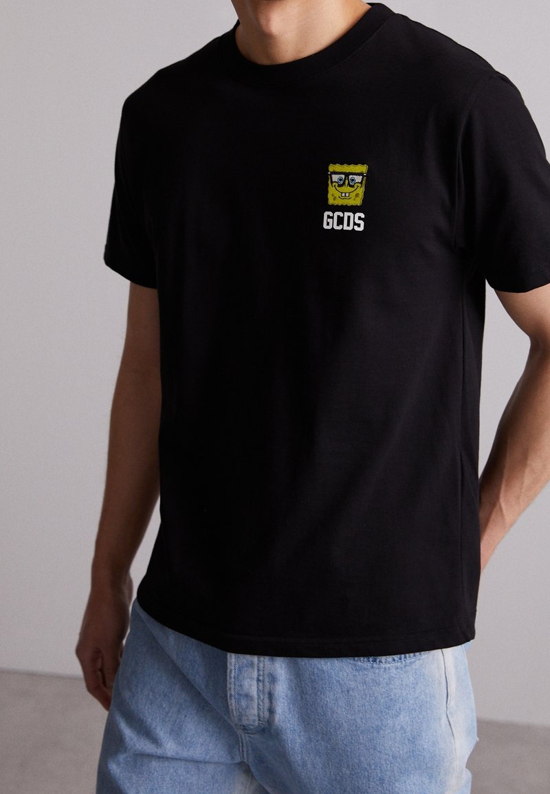Černé bavlněné tričko s kulatým výstřihem, na hrudi s grafickým potiskem žlutého SpongeBoba a textem "GCDS". Krátké rukávy, volný střih.
