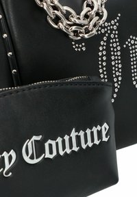 Bolso de mano de cuero sintético negro con herrajes plateados, una correa de cadena gruesa y detalles de tachuelas. Incluye un pequeño estuche con texto de logo.