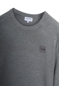 Maglione grigio a maglia con collo tondo, polsini a costine e una patch con logo testurizzato sul petto. Realizzato in un morbido mix di materiali.