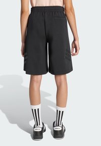 Pantaloncini sportivi neri con cintura elastica, caratterizzati da tre strisce orizzontali su ogni lato, tessuto liscio e una tasca posteriore.