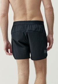 Svarta badshorts med elastisk midja, minimalistisk design och en liten logotag på nedersta vänstra bakpartiet. Lättviktig, slät tyg.