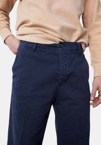 Pantaloni in cotone blu navy con fronte piatto, chiusura con zip e due tasche anteriori, design slim fit e texture leggera.