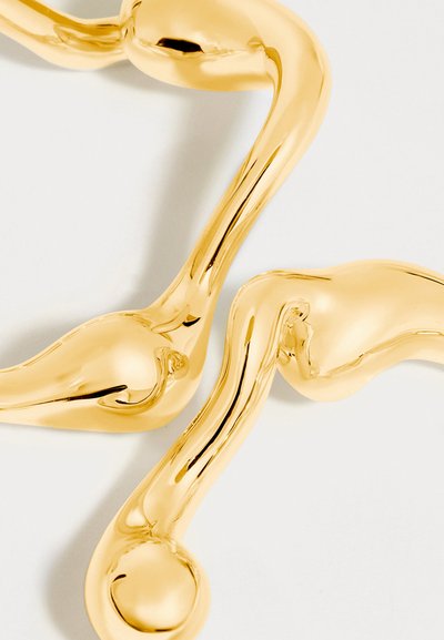 Polished gold-tone earrings with irregular, wavy shapes and rounded ends on a white background.