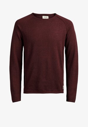 Pull à manches longues col rond de couleur bordeaux foncé avec une petite étiquette de marque en tissu près de l’ourlet côté gauche.