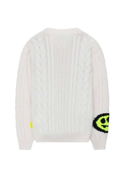 Maglione color crema con design a trecce, polsini a coste e una toppa a forma di faccina sorridente nera e gialla fluorescente sul maniche sinistro.