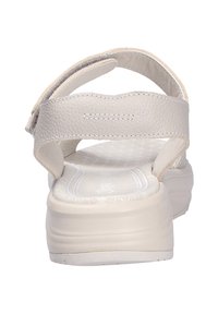 Sandalias beige con parte superior de cuero texturizado, correas ajustables de velcro, suela acolchada y un diseño de perfil bajo.