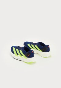 Tengerkék futócipők, neon zöld csíkokkal. Könnyű kialakítással, párnázott fehér talppal és narancs kiegészítőkkel rendelkezik.