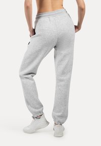 Lys grå sweatpants lavet af blødt stof. Har en ribbet talje og elastiske manchetter, samt et logo label detaljer på siden.