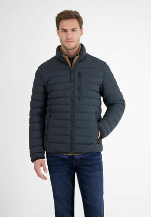 Donzen jas in donkergrijs met horizontaal gestikte delen, hoge kraag, voorsluiting met rits en zijzakken. Draag het over een marineblauw shirt en jeans.
