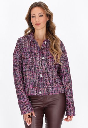 Giacca in tweed viola e rosa con colletto, chiusura a bottoni e maniche lunghe. Caratteristico motivo testurizzato su tutta la superficie.