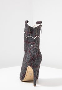 Gray tweed ankle boot with a checkered pattern, pointed toe, and a high stiletto heel. Features a contrasting white trim and zipper detail.