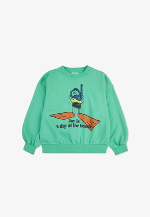 Felpa verde menta con maniche lunghe e orlo a coste. Presenta una grafica di un personaggio che fa snorkeling, con la scritta "La gioia è una giornata in spiaggia."