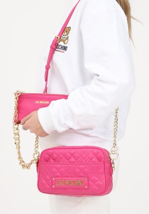 Różowa pikowana torebka na ramię z złotym łańcuszkiem i detalami z logo. Zawiera odpinaną mini saszetkę o dopasowanym wzorze i paskach.