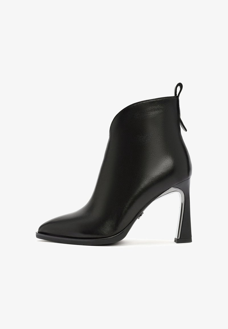 Bottine noire en cuir avec bout pointu, talon haut évasé et languette à l'arrière, vue de profil sur fond blanc.