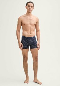 Boxers bleu marine avec un motif, fabriqués en tissu doux. Présente une taille contrastante avec l'étiquette "TOM TAILOR."