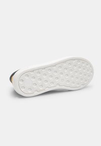 Suela de zapatilla blanca con un patrón hexagonal texturizado. Presenta un borde liso y un color de contraste cerca del talón. Material de goma duradera.