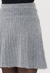 Grå ribbestrikket skjørt med en tettsittende livlinje og utsvingt kant, med en myk tekstur og kne-lengde design.