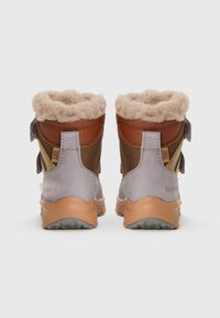 Bottines marron et grises avec une douce doublure en fourrure crème, des accents en cuir et une semelle en caoutchouc texturée. Sangles latérales ajustables pour un meilleur maintien.