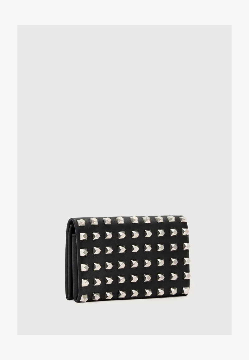 Carteira de couro preto com rebites em forma de pirâmide prateados dispostos em um padrão de grelha, apresentando um design dobrável e textura suave.