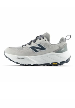Chaussure de sport New Balance grise et blanche avec semelle noire, amorti Fresh Foam, semelle extérieure Vibram et languette au talon.