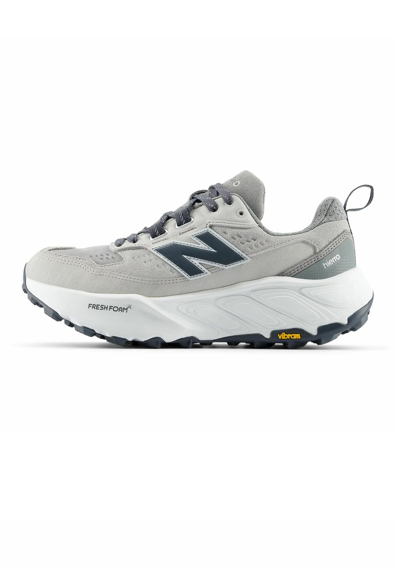 Chaussure de sport New Balance grise et blanche avec semelle noire, amorti Fresh Foam, semelle extérieure Vibram et languette au talon.
