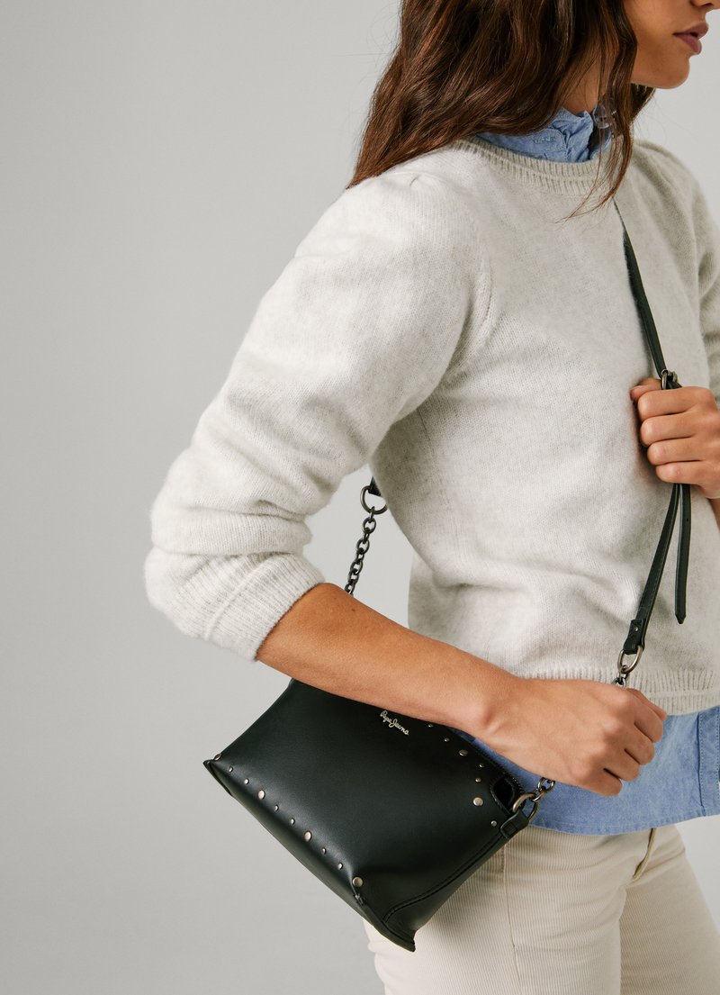 Sac en cuir noir à bandoulière avec des clous en métal argenté sur le côté, surface texturée et sangle en chaîne réglable.