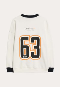 Sudadera blanca con un gran gráfico en negro y naranja del "63" en la espalda, con el logo de "McLaren" arriba. Cuello y puños de canalé negros.