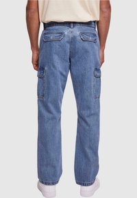 Pantalones cargo de mezclilla en azul medio, con dos bolsillos laterales y dos bolsillos traseros. Corte holgado con pierna recta y dobladillos remangados.