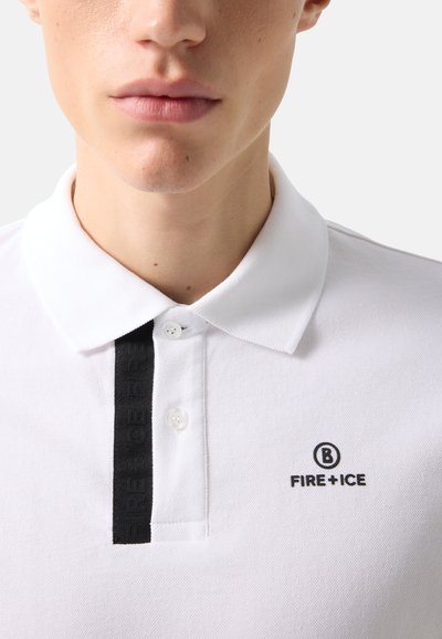 Close-up of a person wearing a white polo shirt with a black "FIRE + ICE" logo on the chest and a black button strip detail.