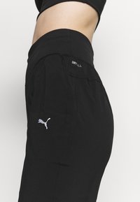 Schwarze Sporthose aus leichtem Material, mit breitem Bund, DRYCELL-Logo und einem kleinen weißen Puma-Logo als Akzent.